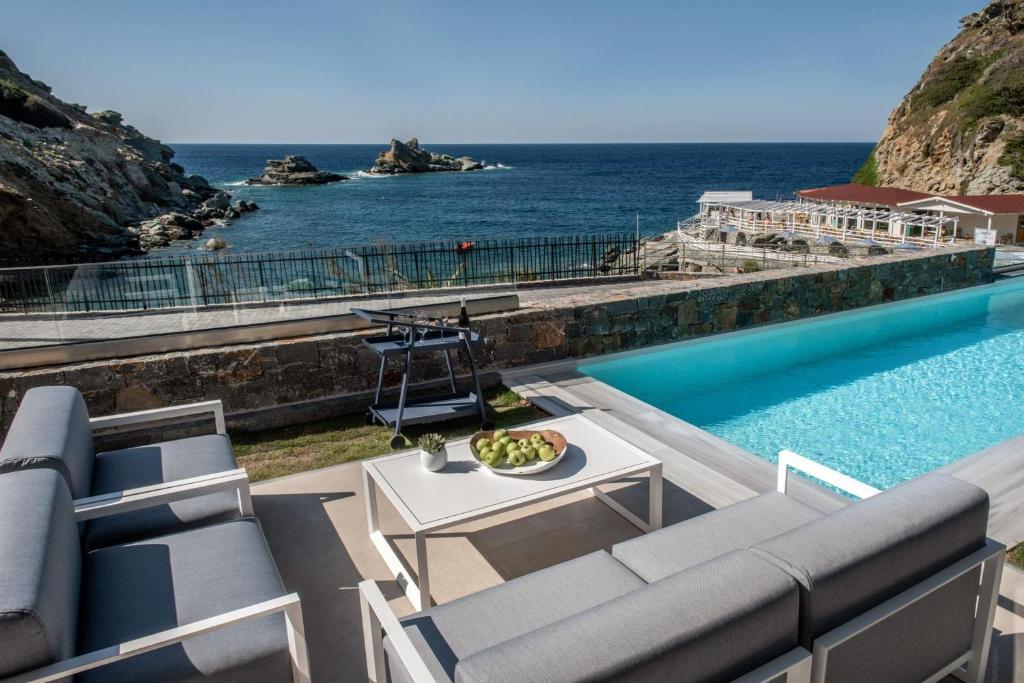 basen z krzesłami i stołem oraz ocean w obiekcie Made By The Sea Villas 8 BDRM w mieście Ligaria