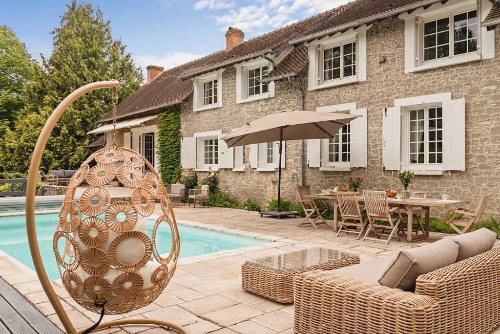 une maison avec une piscine et une terrasse avec un parasol dans l'établissement Elégante demeure avec piscine à 1h20 de Paris, à Estouy