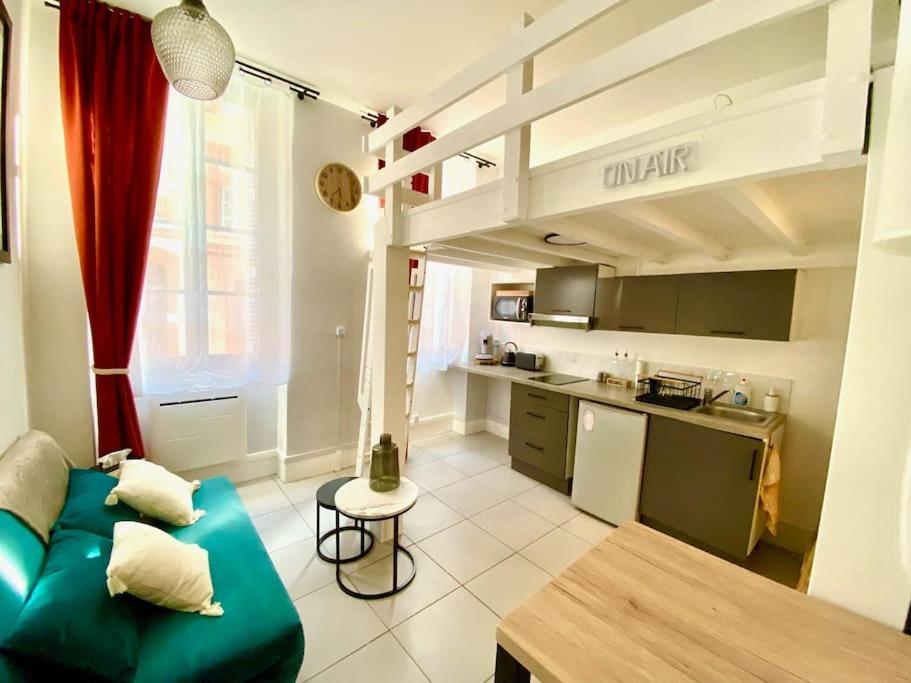 un salon avec un canapé vert et une cuisine dans l'établissement Studio cosy jardin des plantes, à Toulouse