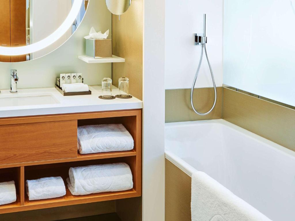 a bathroom with a bath tub and a sink at Sofitel Luxembourg Europe in Luxembourg