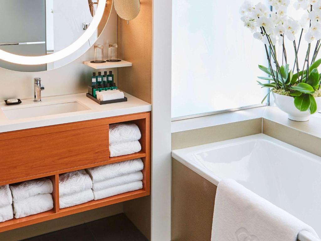 a bathroom with a tub and a sink and a mirror at Sofitel Luxembourg Europe in Luxembourg