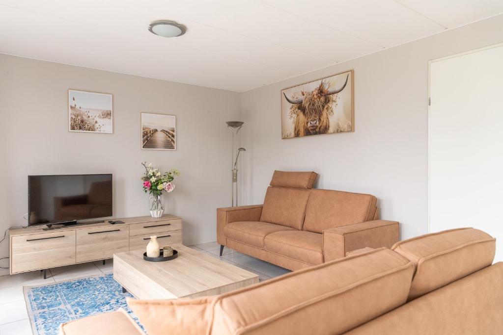 Una sala de estar con un sofá y un televisor. en Bohemien Resort 3, en Sint Maartenszee