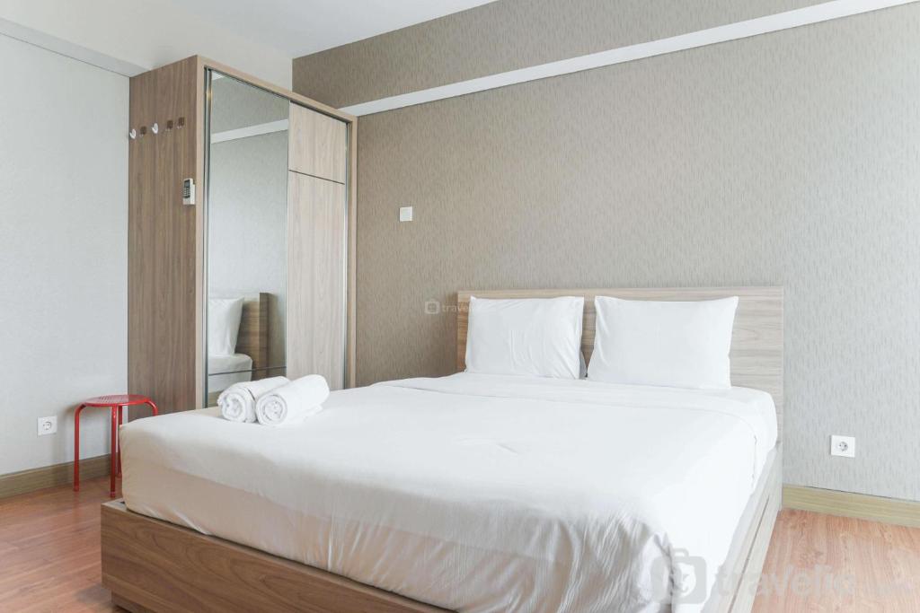 a bedroom with a large white bed and a mirror at Comfortable and Nice Studio Room Apartement at H Residence By Travelio in Jakarta