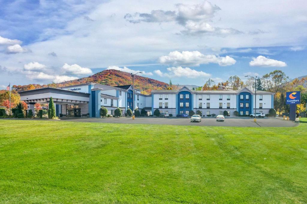 a large building with a green field in front of it at Comfort Inn Asheville East-Blue Ridge Pkwy Access in Asheville