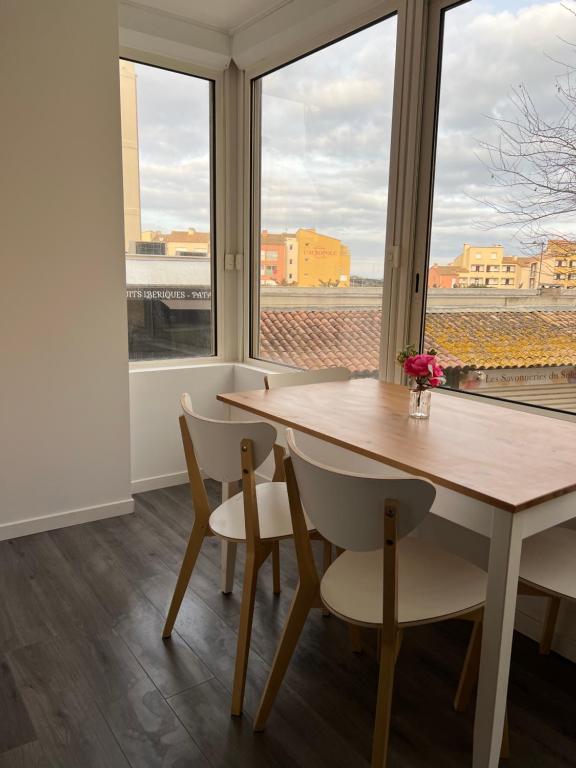 une salle à manger avec une table, des chaises et des fenêtres dans l'établissement Studio à 100m de la mer, au Cap d'Agde