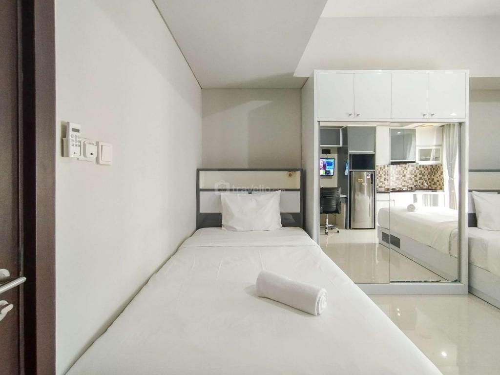 a white room with a bed and a kitchen at Strategic and Comfy Studio at Skyland City Jatinangor Apartment By Travelio in Sumedang