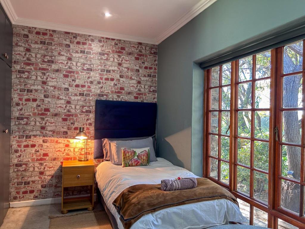 a bedroom with a bed and a brick wall at Tzamenkomst River Lodge in Colesberg