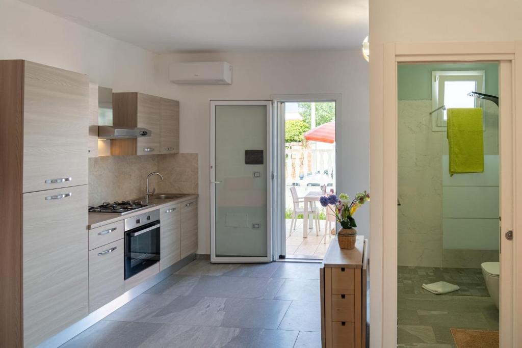 a kitchen with white cabinets and a door leading to a patio at Casa Vacanza Mario 1A a 180 mt dal mare di Punta Prosciutto in Punta Prosciutto