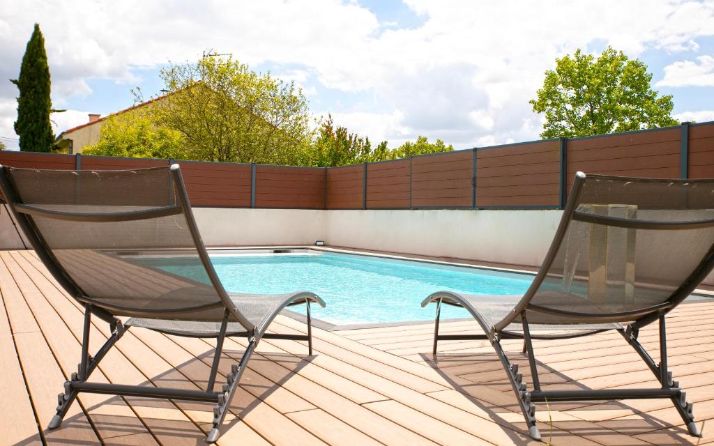 - deux chaises assises sur une terrasse à côté d'une piscine dans l'établissement La Rochette - Magnifique Villa calme et paisible, à Le Loroux-Bottereau