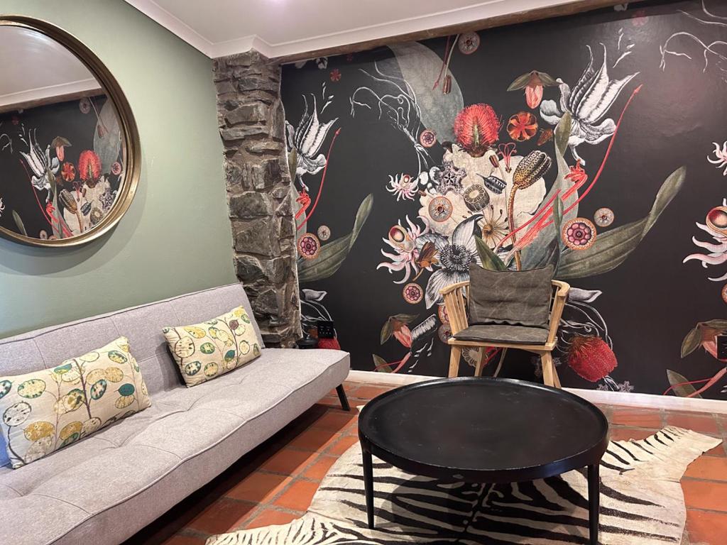 a living room with a couch and a flower mural at Tzamenkomst River Lodge in Colesberg