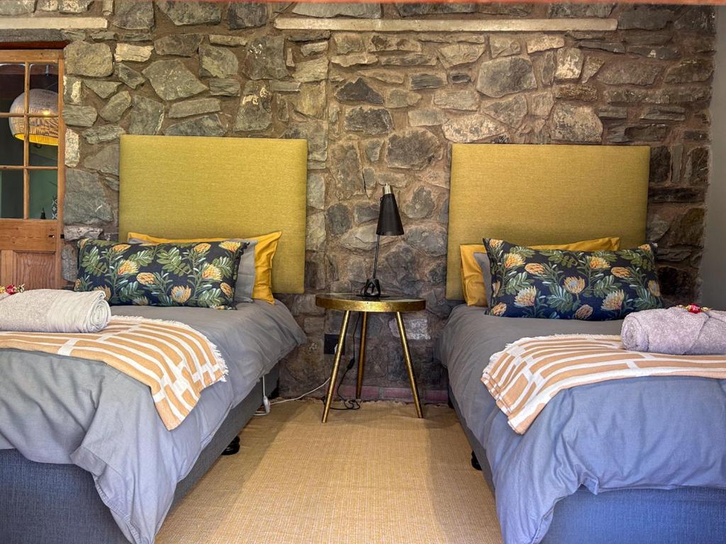 two beds in a room with a stone wall at Tzamenkomst River Lodge in Colesberg