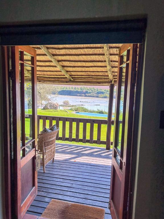 an open door to a porch with a view of the water at Tzamenkomst River Lodge in Colesberg