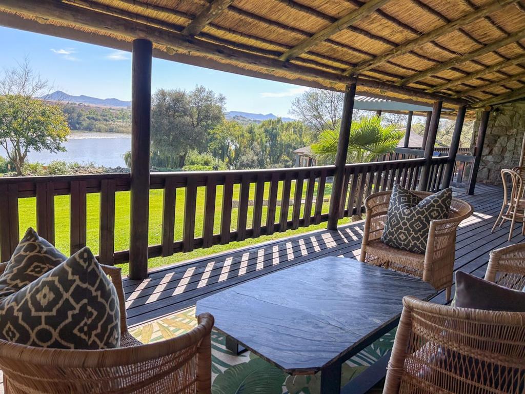 a patio with a table and chairs on a deck at Tzamenkomst River Lodge in Colesberg