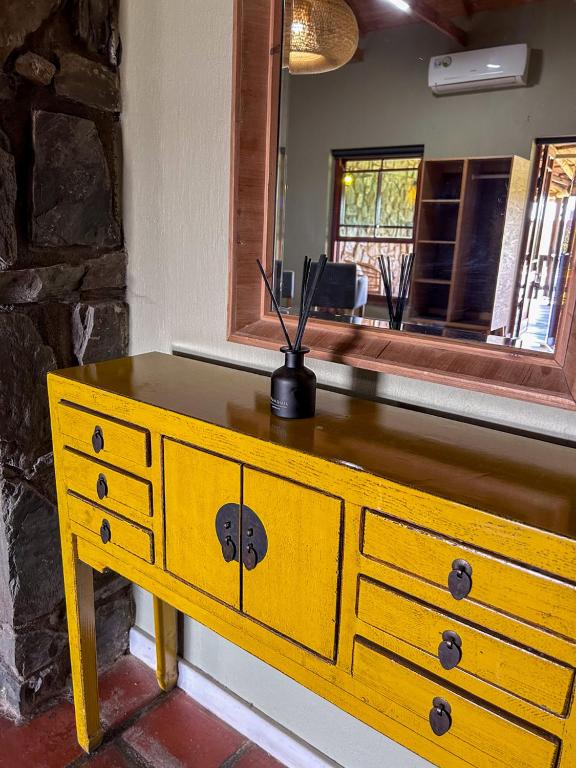 a yellow dresser in a room with a mirror at Tzamenkomst River Lodge in Colesberg