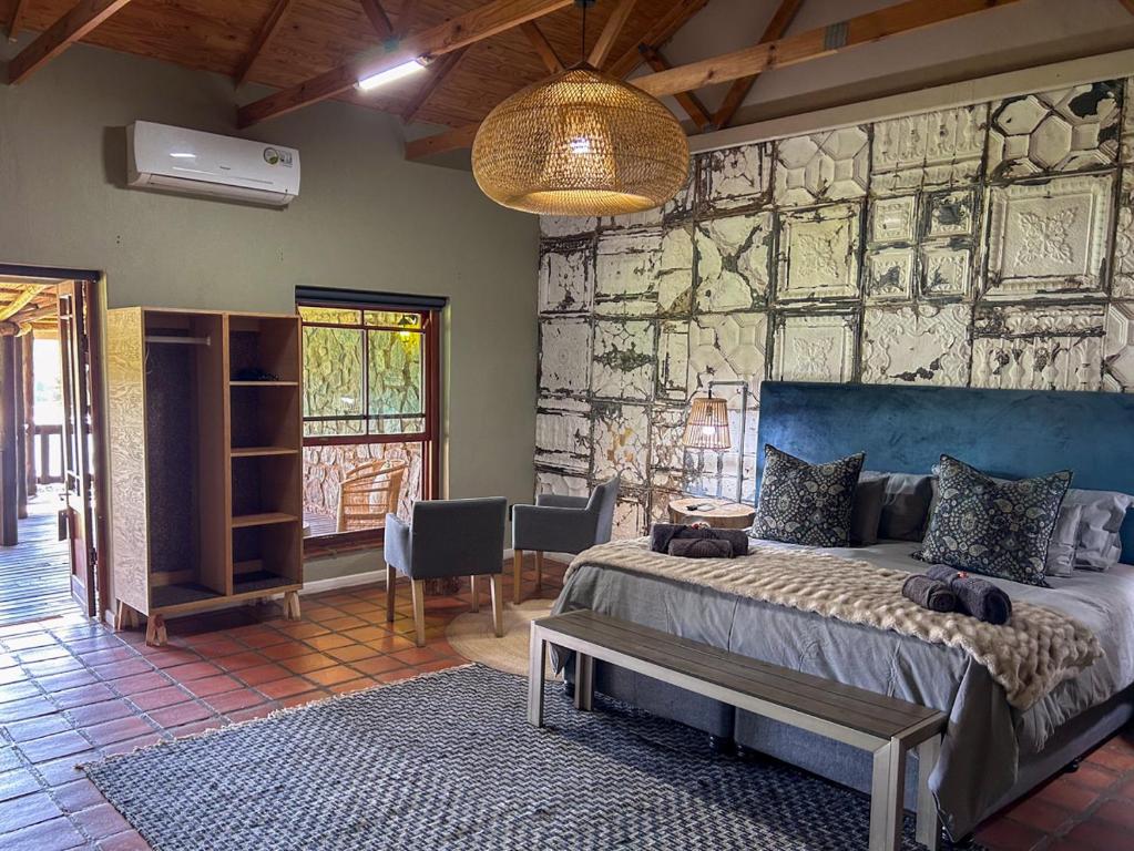 a bedroom with a bed and a stone wall at Tzamenkomst River Lodge in Colesberg