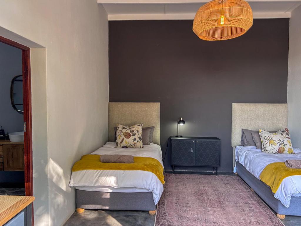 a bedroom with two beds and a chandelier at Tzamenkomst River Lodge in Colesberg