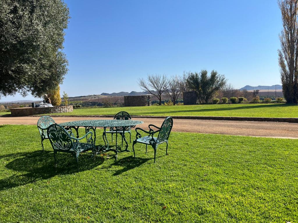a table and chairs sitting in a grass field at Tzamenkomst River Lodge in Colesberg