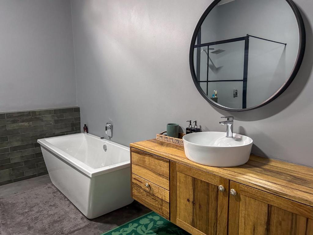 a bathroom with a tub and a sink and a mirror at Tzamenkomst River Lodge in Colesberg