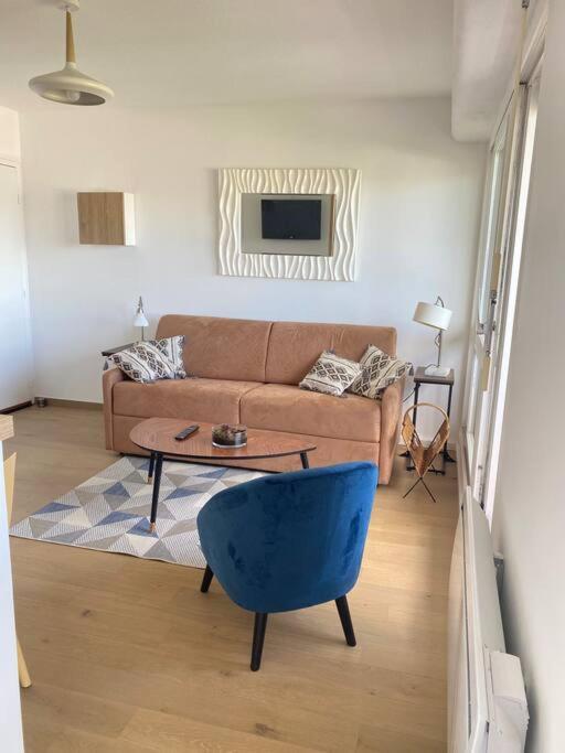 un salon avec un canapé et une chaise bleue dans l'établissement Studio avec loggia, classé 2 étoiles, situé sur le port, à Courseulles-sur-Mer