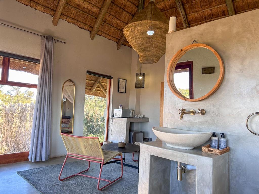a bathroom with a sink and a chair and a mirror at Tzamenkomst River Lodge in Colesberg