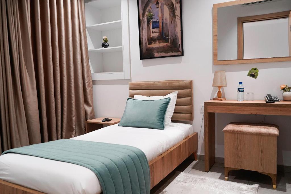 una piccola camera da letto con un letto e una scrivania di Hôtel Suisse Tunis a Tunisi