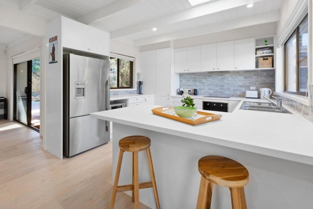a kitchen with a white counter and two stools at Brooks by the bay in Blairgowrie