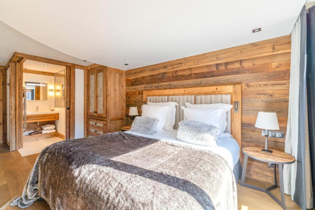 a bedroom with a bed and a wooden wall at Hôtel Les Peupliers in Courchevel