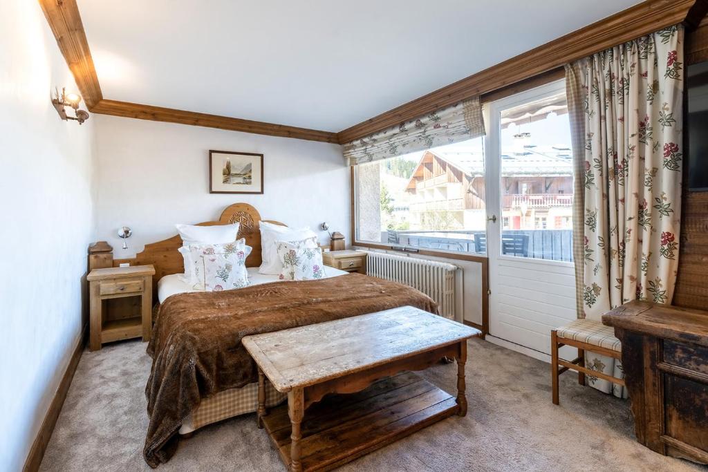 a bedroom with a bed and a window at Hôtel Les Peupliers in Courchevel