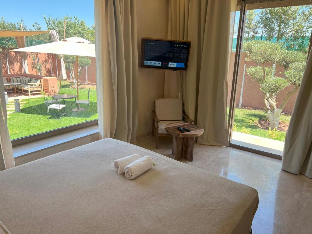 a bedroom with a bed with a television and a large window at Villa Joudia in Azib Oulad Lâdem