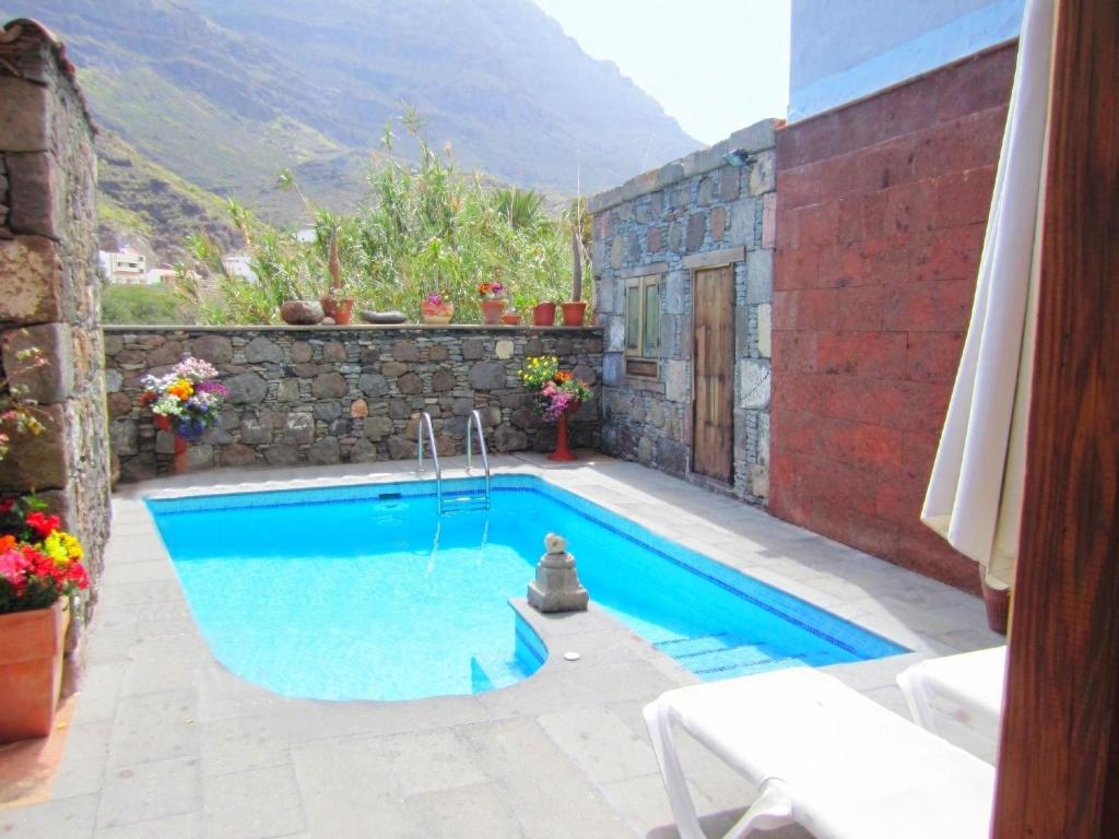a swimming pool in front of a house at La Finca' Landhaus in El Pie de la Cuesta