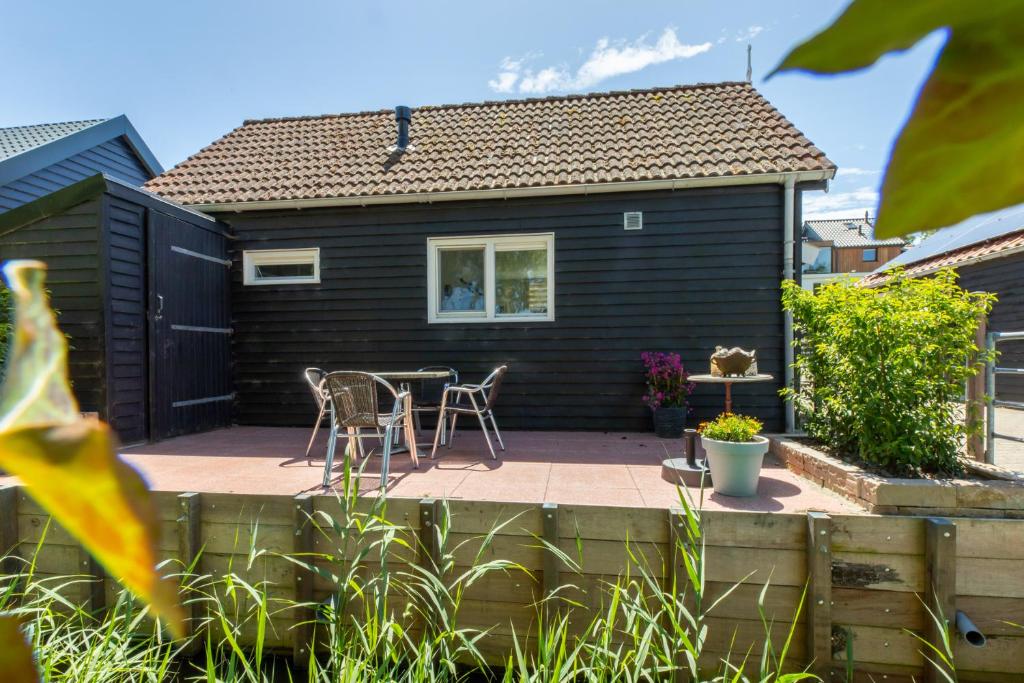 a black house with a patio with a table and chairs at Welcome in - Vakantiehuis - Achterweg 10 Zonnemaire ' Sol e Mar' in Zonnemaire