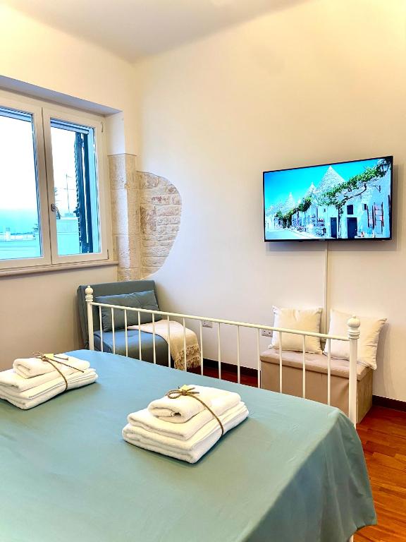 a room with a table and a tv on the wall at Iaru-Bed Experience House in Alberobello