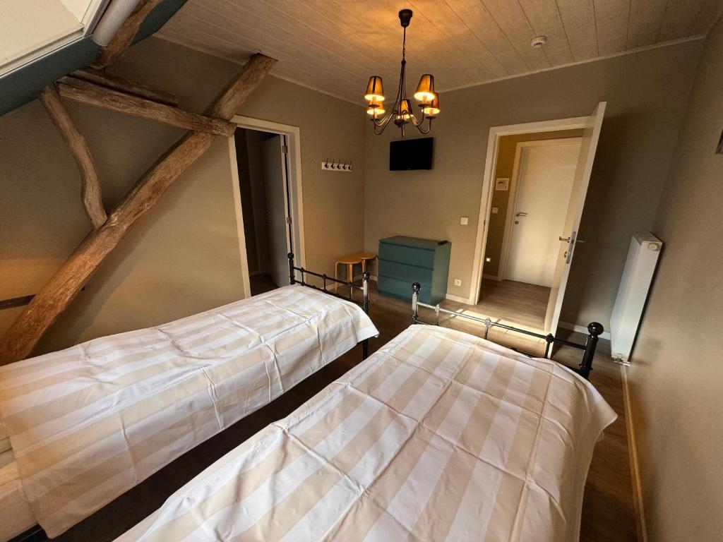 una camera con due letti e un lampadario a braccio di B&B De Vreehoeve a Merksplas