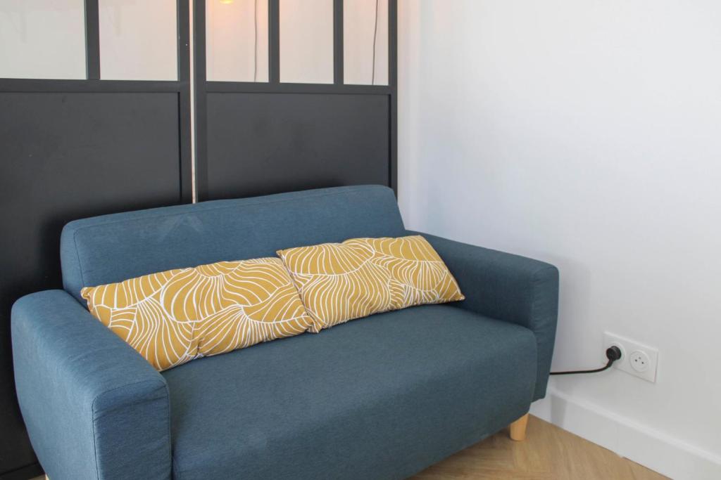 - un canapé bleu avec un oreiller dans l'établissement Practical and pleasant 20 m studio, à Montreuil