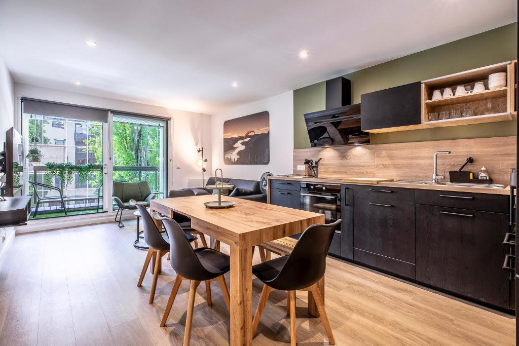 une cuisine avec une table en bois et des armoires noires dans l'établissement Appartement Moderne au Cœur d'Annecy - À Deux Pas du Lac et de la Vieille Ville, à Annecy