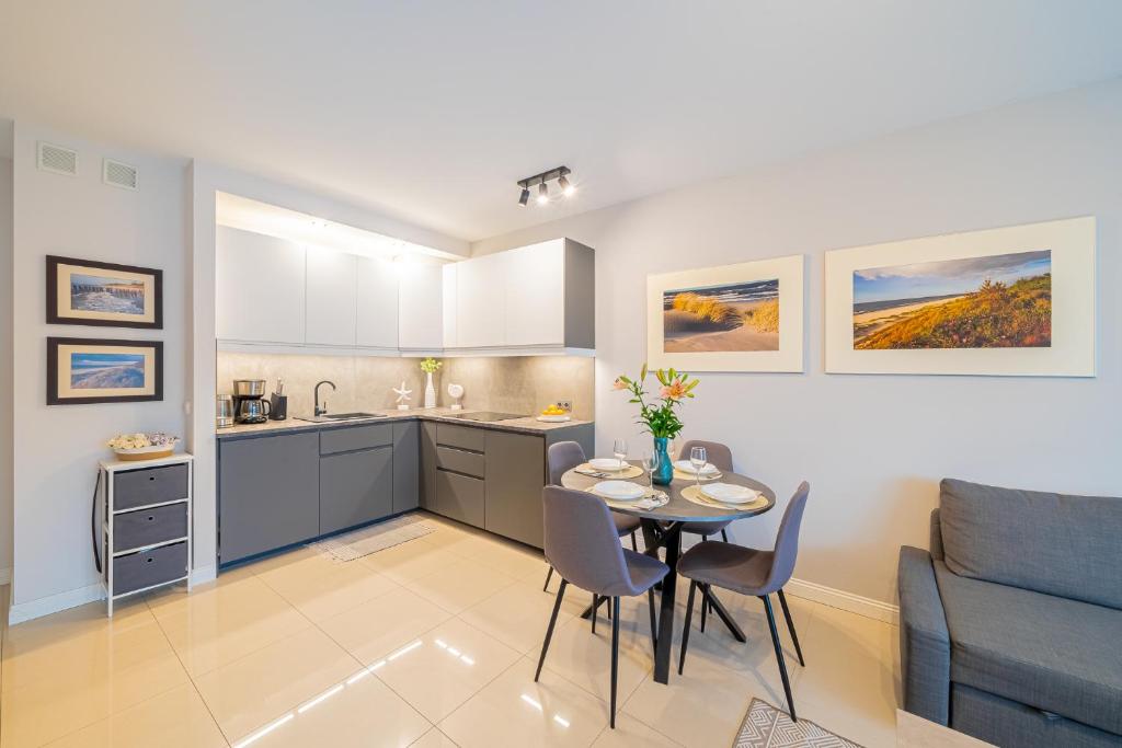 eine Küche und ein Esszimmer mit einem Tisch und einer Couch in der Unterkunft Lulu Apartments - NoMoreRain - Apartament 2-pokojowy Grzybowo - klimatyzacja, Netflix in Grzybowo