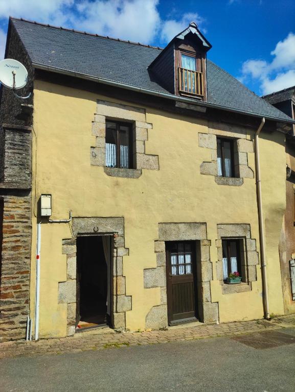 un vieux bâtiment jaune avec une porte et des fenêtres dans l'établissement Maison Josselin proche château, à Josselin