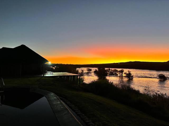 a sunset over a body of water with the sun setting at Tzamenkomst River Lodge in Colesberg