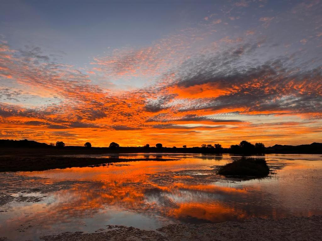 a sunset over a body of water with the sky at Tzamenkomst River Lodge in Colesberg