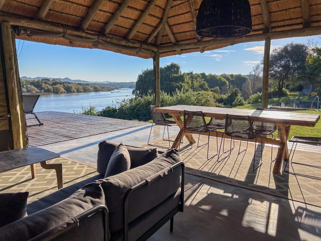 a patio with a table and chairs and a view of a river at Tzamenkomst River Lodge in Colesberg