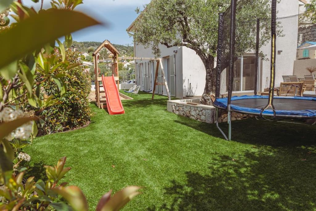 une cour avec une aire de jeux dotée d'un toboggan et d'un trampoline dans l'établissement Villa Jeade, à La Colle-sur-Loup