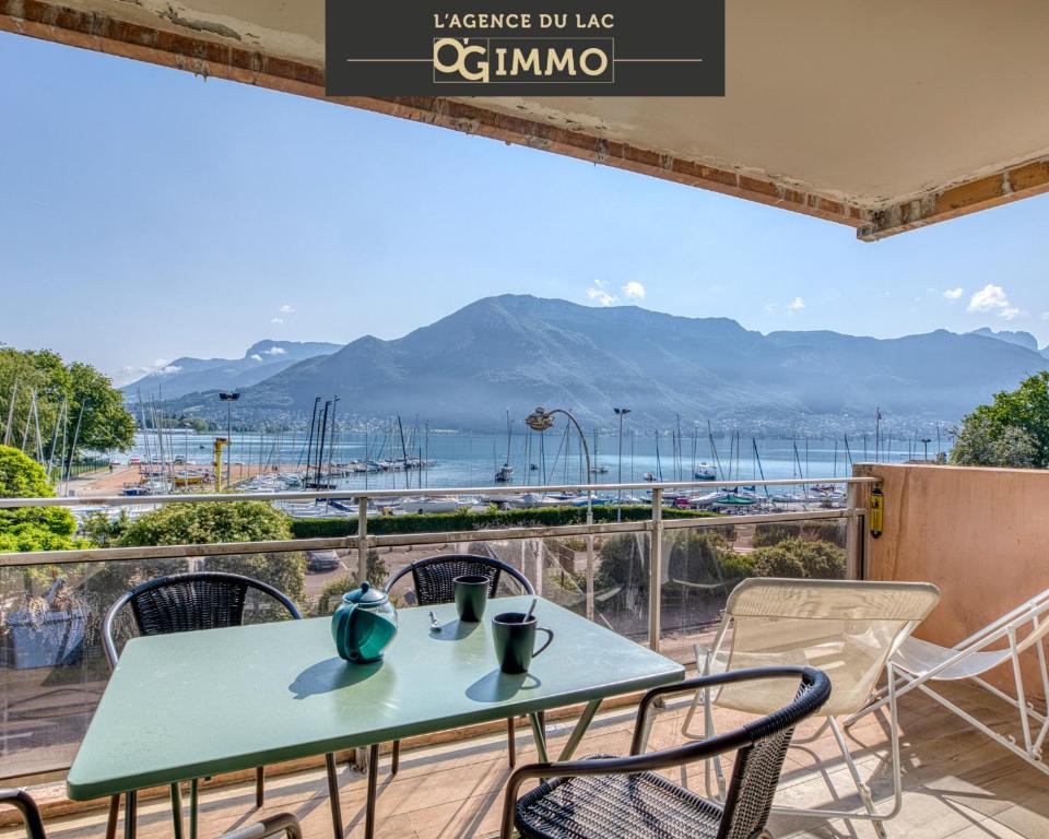 une table et des chaises sur un balcon avec vue sur l'océan dans l'établissement Les mats du lac, à Annecy
