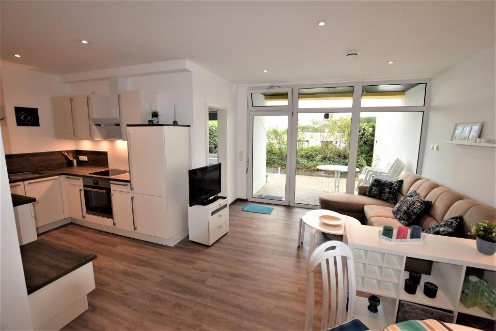 ein großes Wohnzimmer mit Couch und Küche in der Unterkunft Hohes Ufer Sandburg in Hohwacht