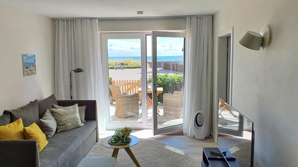 a living room with a couch and a sliding glass door at Meeresblick Appartement 33 H3 WE 33 in Hohwacht