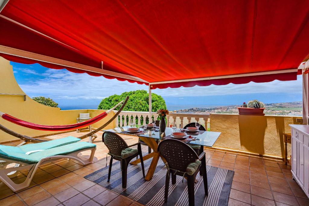 un patio con mesa, sillas y sombrilla roja en Balcon Smart Home Hi-End Services Media Streaming, en Adeje