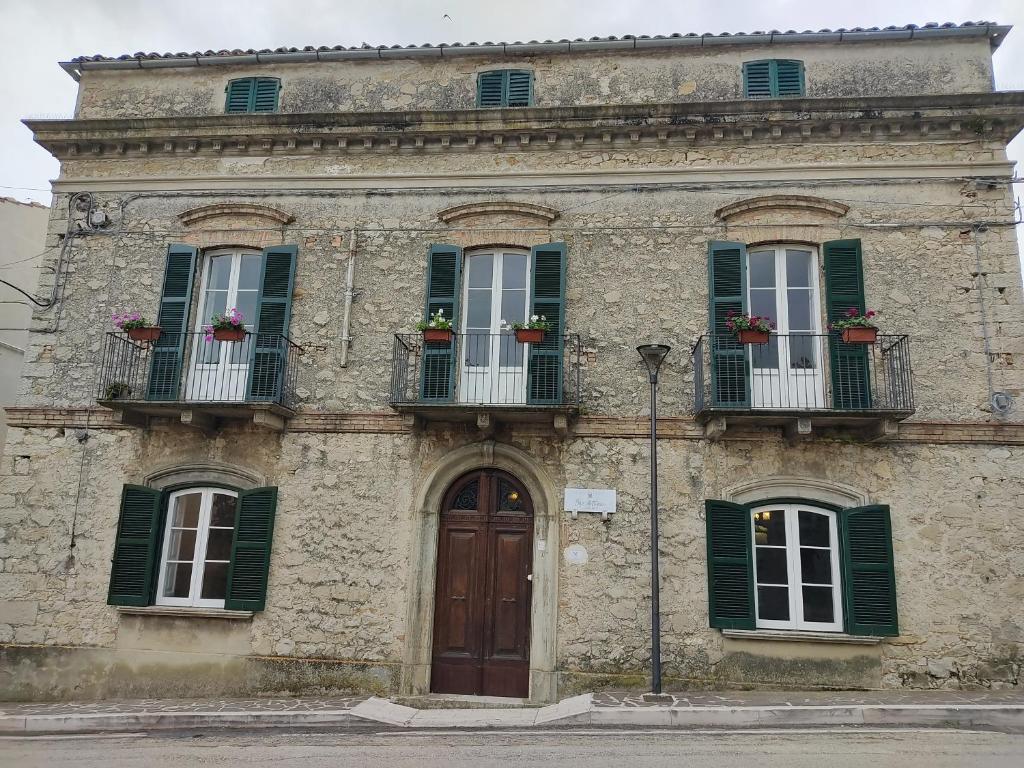 an old building with green shuttered windows and a door at B&B Don Antonio in Civitella Casanova