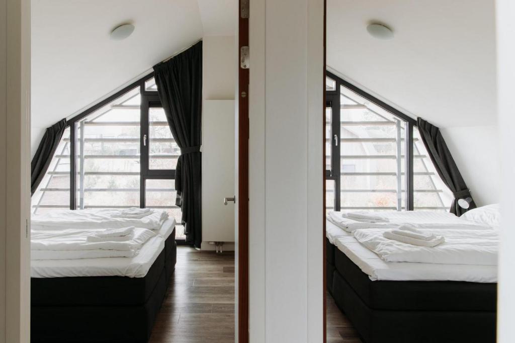 Dos camas en una habitación con dos ventanas. en Villa Duinhuis Zee, en Egmond aan den Hoef