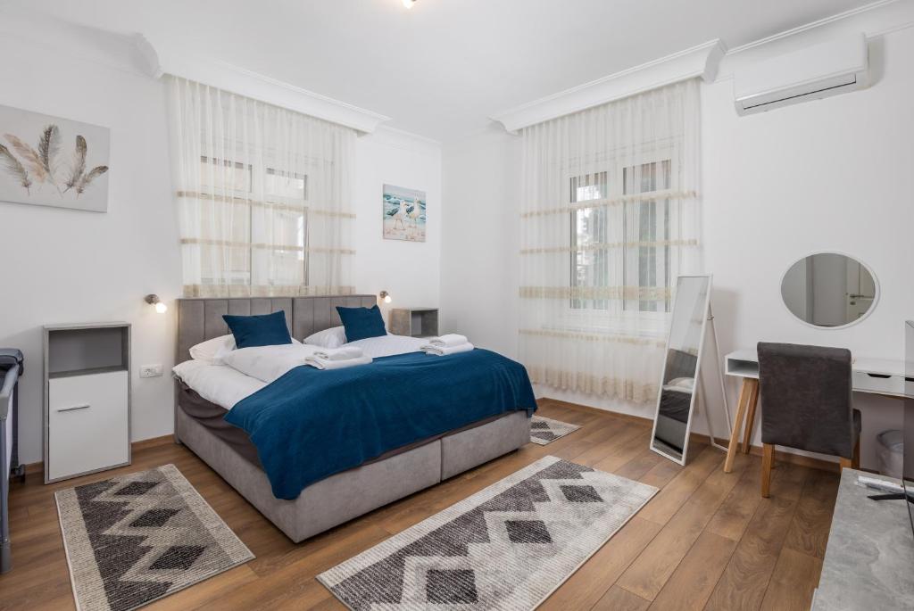 a white bedroom with a bed and a desk at Amelia & Julia apartments in Rijeka