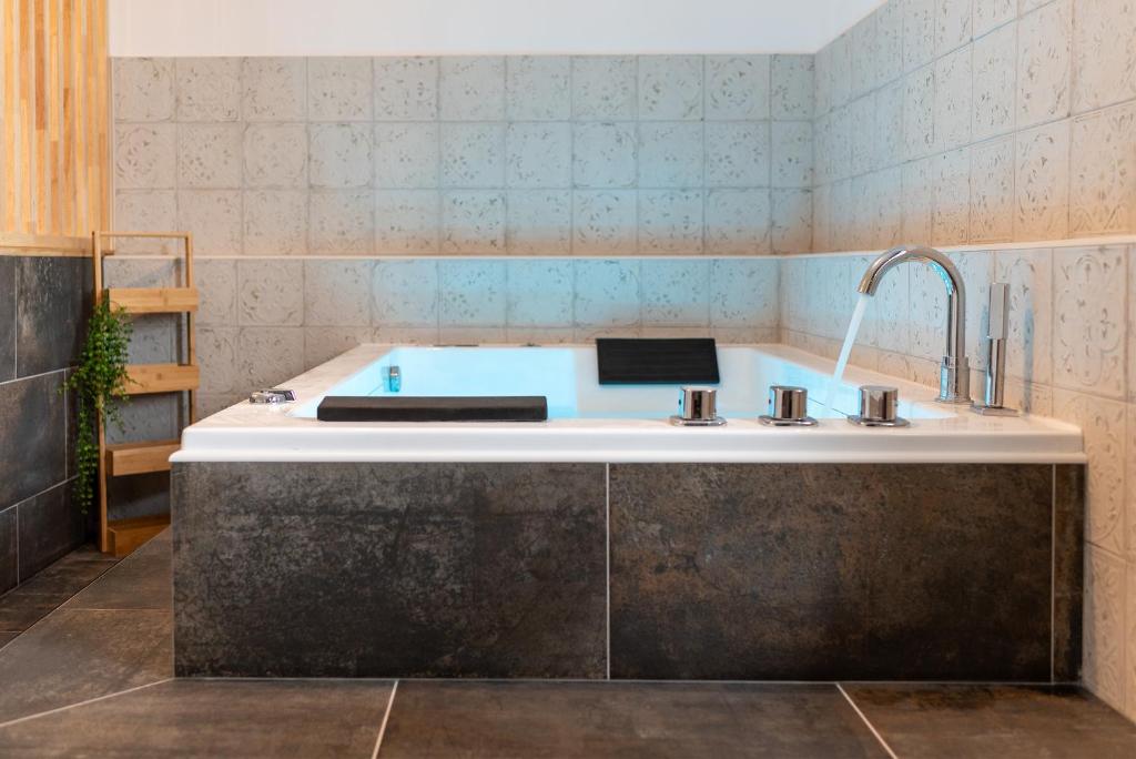 a bathroom with a bath tub with a sink at Appartement Premium jacuzzi terrasse climatisation in Frouzins