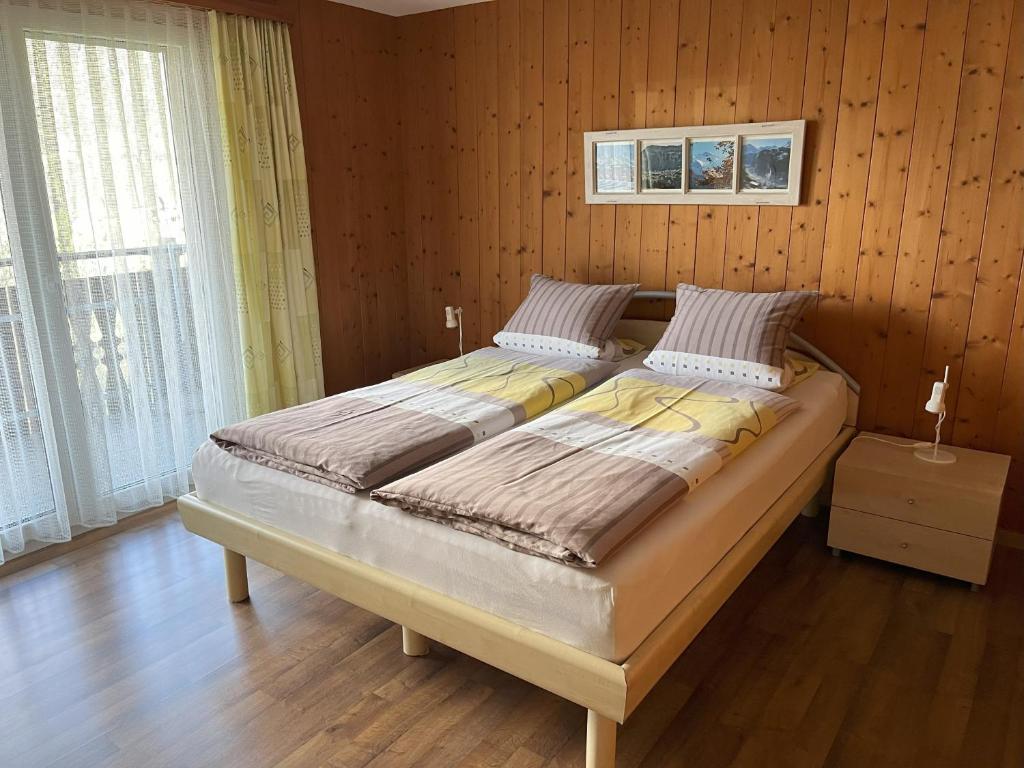 a large bed in a room with wooden walls at Chalet Gerbera in Wengen